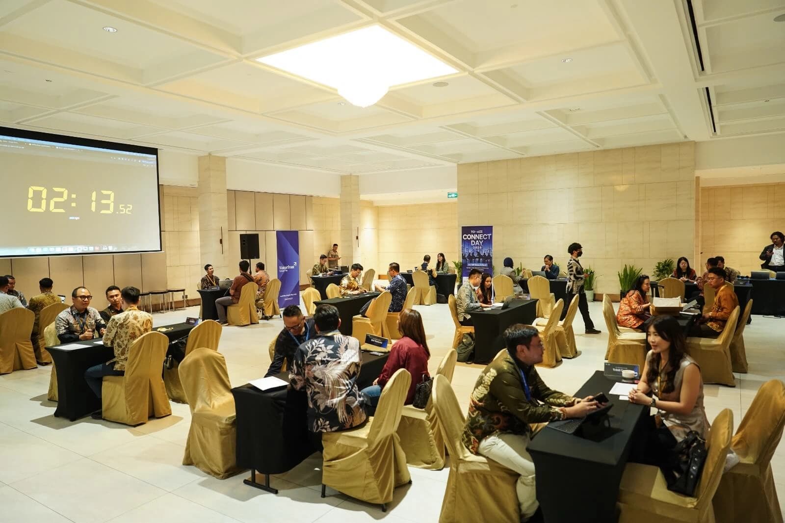 Para profesional bisnis berjabat tangan dan berbincang dalam acara networking dengan latar gedung kota saat senja